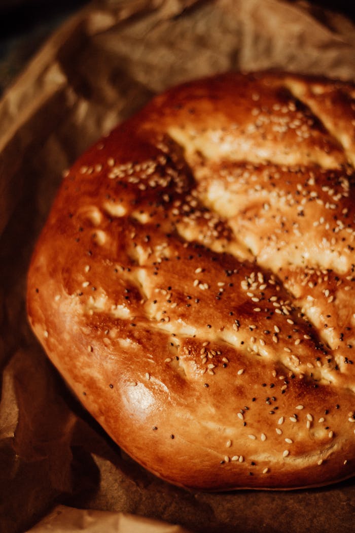 about-us Close-up of rustic homemade bread with sesame seeds, freshly baked on craft paper.